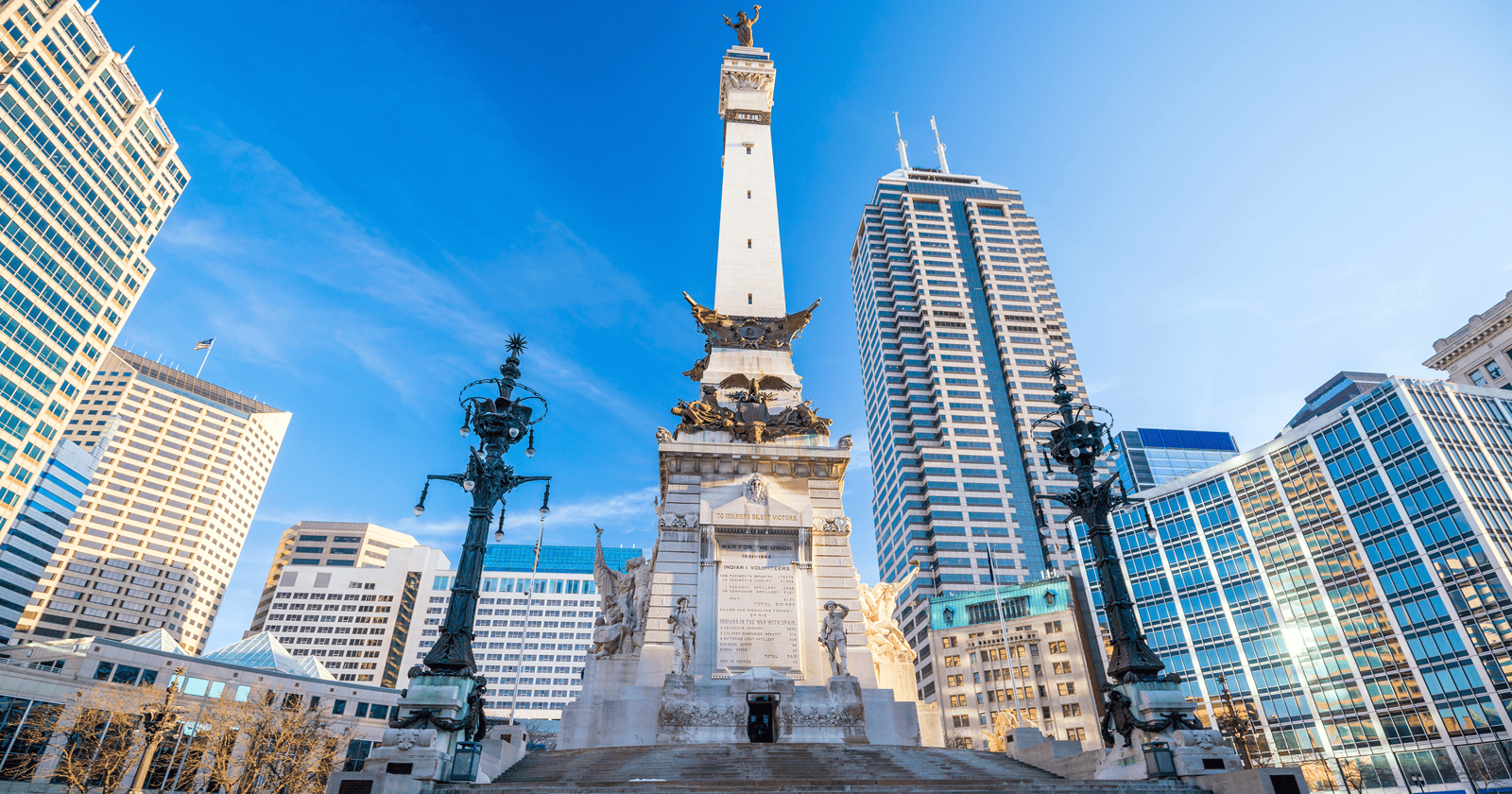 A monument in the middle of a city with tall buildings.