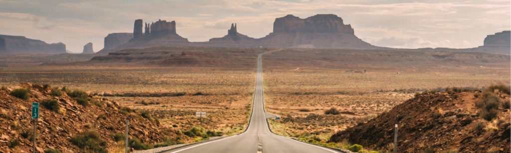 Banner image of a stretch of highway crossing a desert.