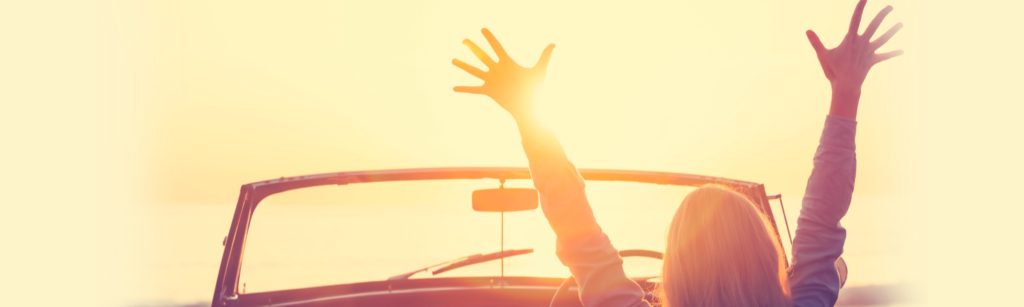 Banner: Silhouette of a woman in her car raising her hands towards the sun