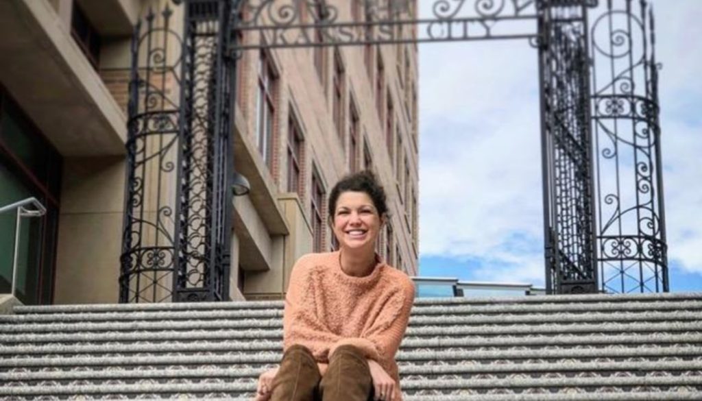 Photo of healthcare worker Lauren Brennan outdoors smiling for the camera while sitting on steps