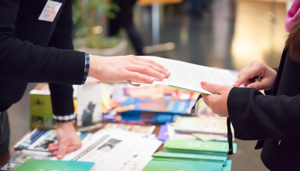 Image: Image of Professional giving someone information at a conference/tradeshow/networking event