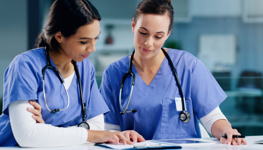image: two nurses reviewing a chart.