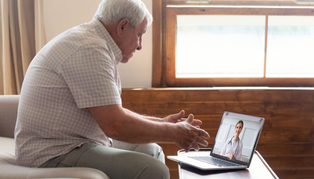 Picture of an older man speaking to a healthcare professional through webcam as he participates in telemedicine