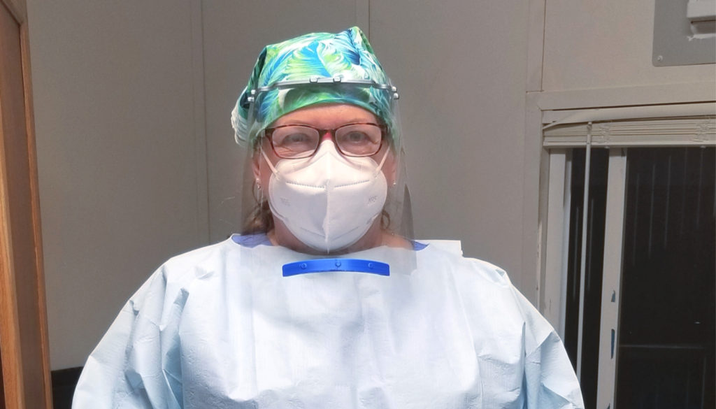Image of registered nurse, Nancy, posing in full ppp gear to defend against covid-19