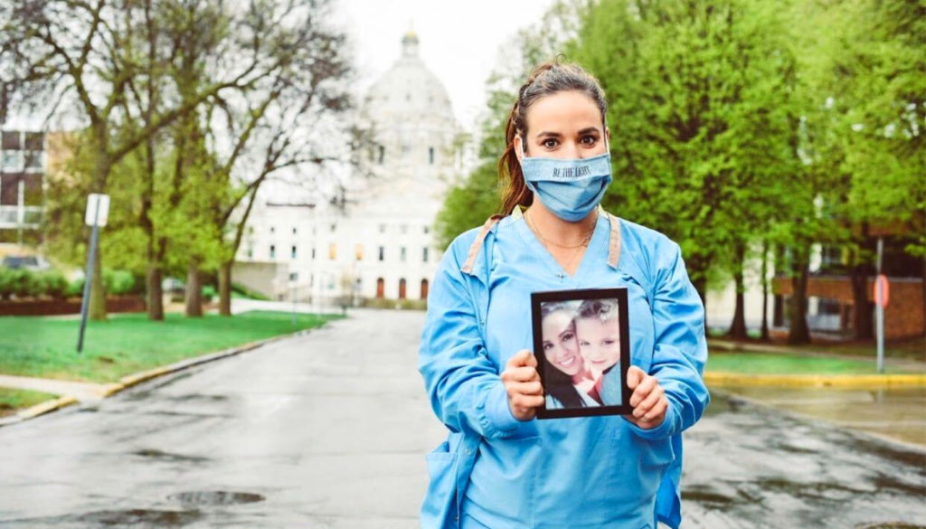 Image of nurse Kandyce, posing outside for the camera with picture of a loved on lost to Covid-19