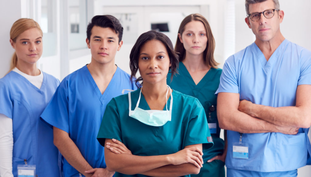 Image of five nurses posing towards the camera with serious face and arms crossed