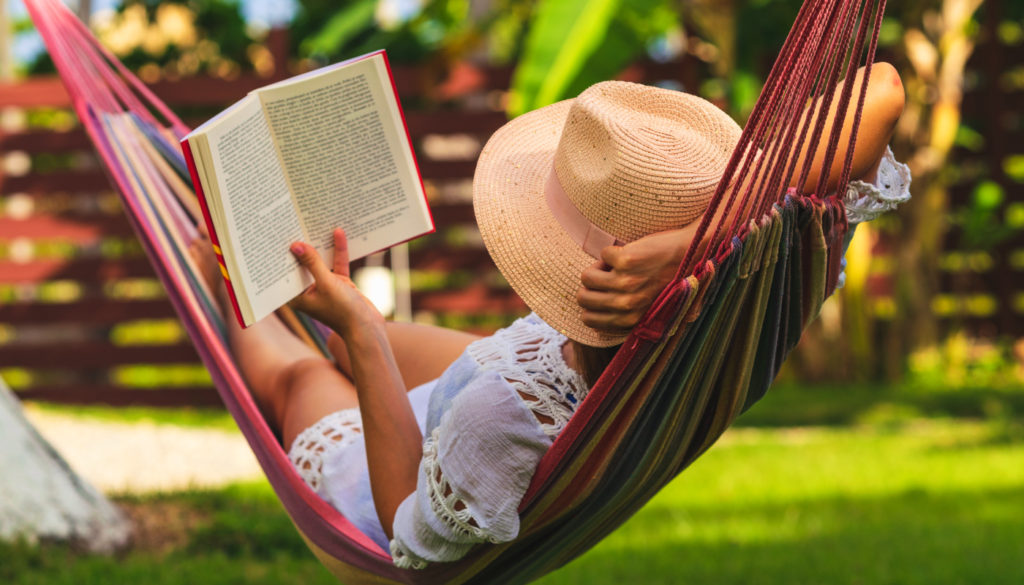 image of woman laying in a hammock reading a book
