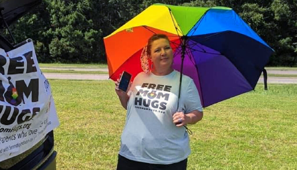 Image: Care More Spotlight: photo of nurse, Lisa Owens, holding a rainbow umbrella offering free mom hugs
