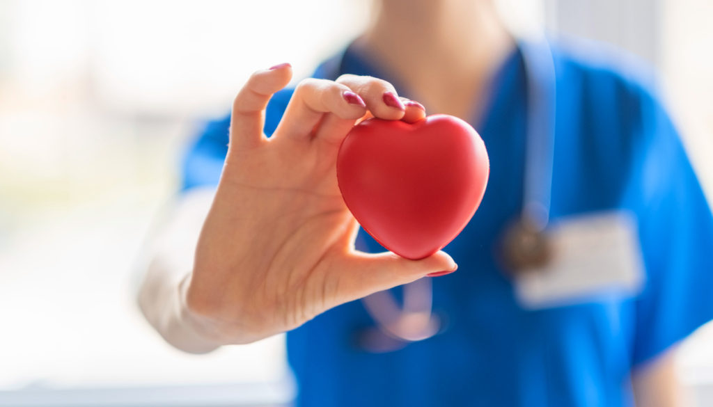 Image: Nurse holding an object in the shape of a heart celebrating Valentine's Day