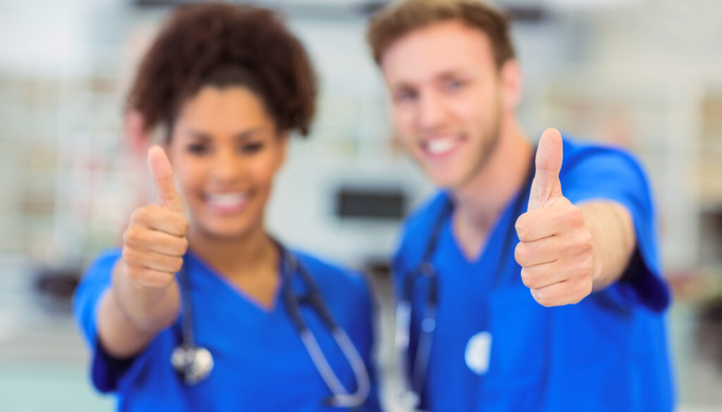 Image: Two nurses smiling with thumbs up.