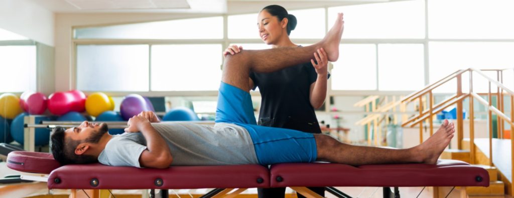 Image: Physical therapist helping a patient to improve range of motion in their leg.