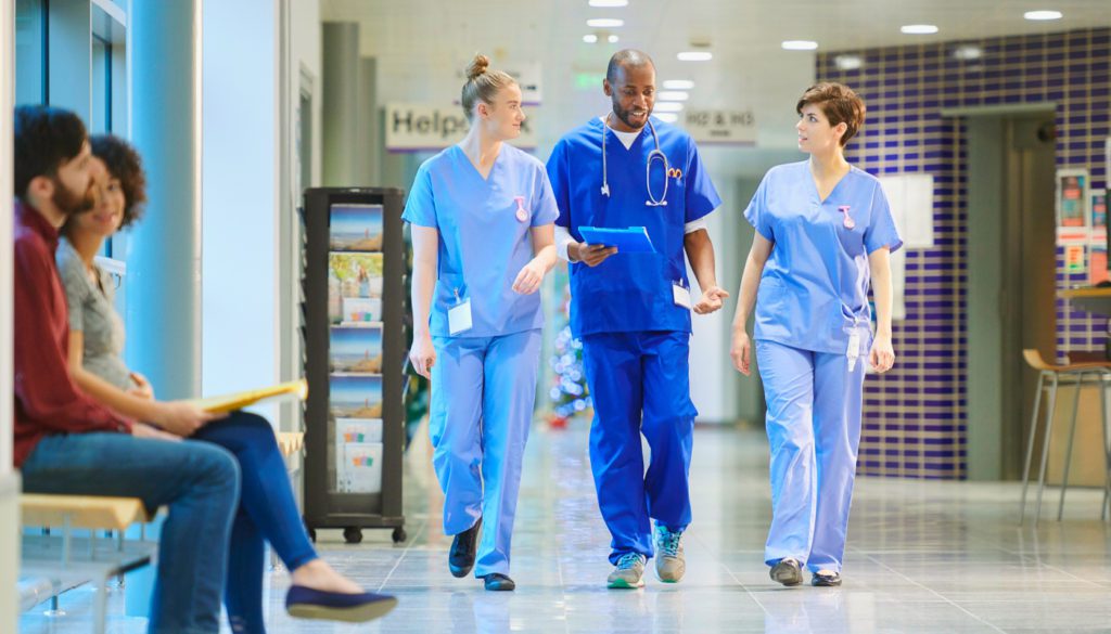 image of three nurses walking through the hospital towards camera while talking