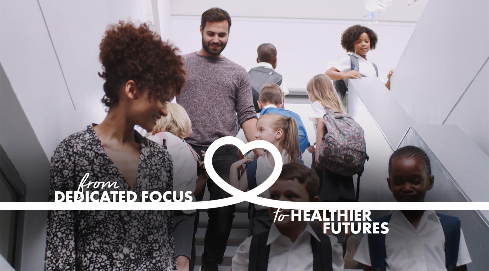 banner image of a teacher smiling at a boy with parents and children behind them and the caption "from dedicated focus to healthier futures".
