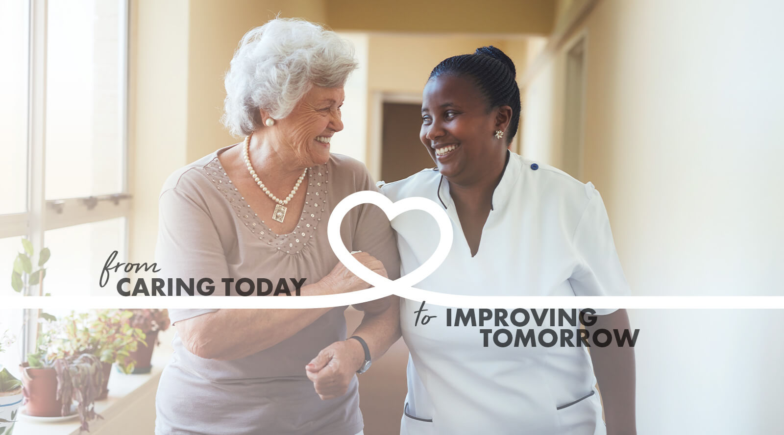 Image of an elderly woman being supported by a woman as each smiles at the other