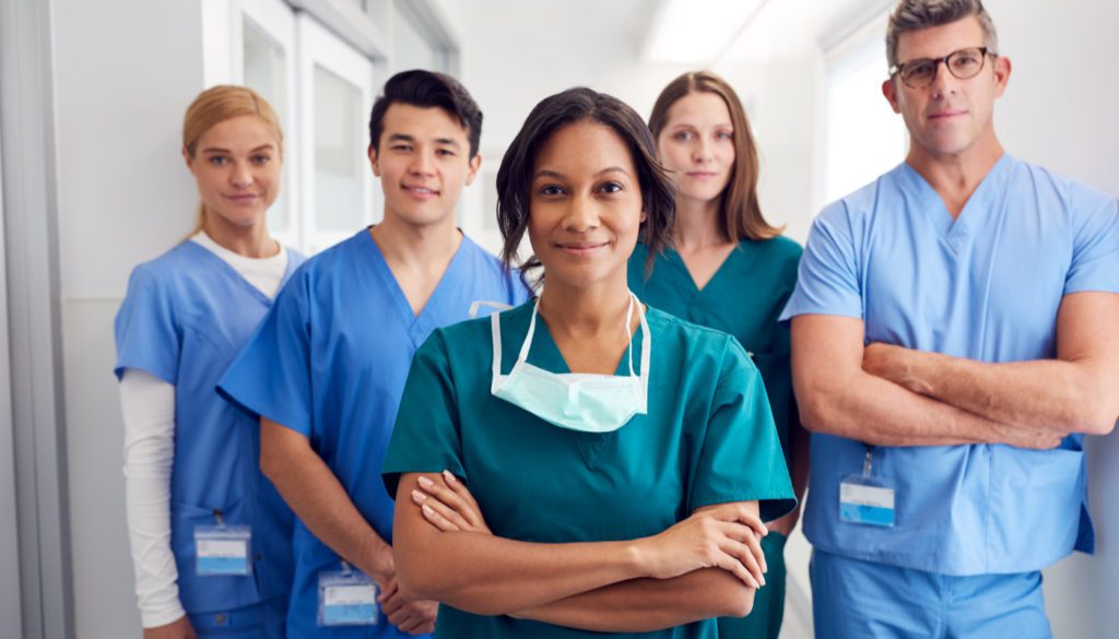 image of five nurses looking confidently at the camera while wearing different colored hospital scrubs