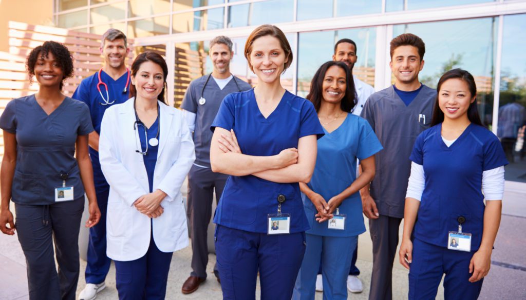 Image of several healthcare professionals posing for the camera outside of the hospital