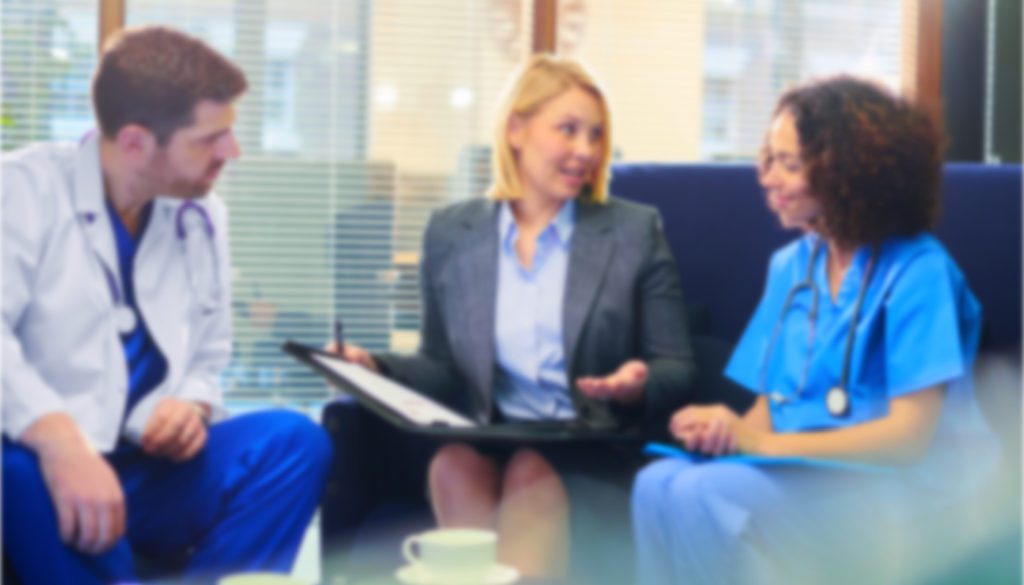 image of a woman professional sitting in an office discussing a topic with two healthcare professionals