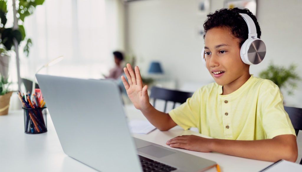 image of a boy wearing headphones speaking to someone through his laptop