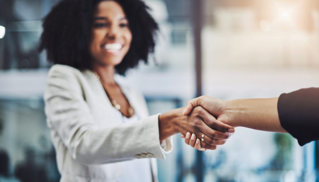 image of a woman shaking hands with another while smiling