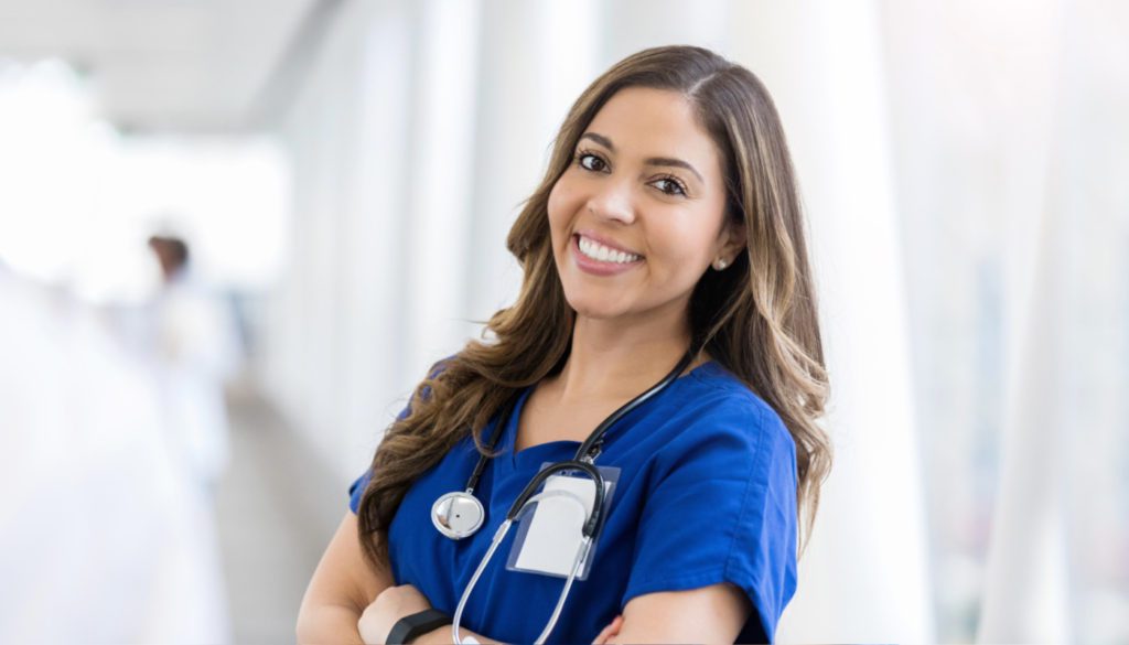 Image of a nurse smiling toward the camera while wearing scrubs and a stethoscope