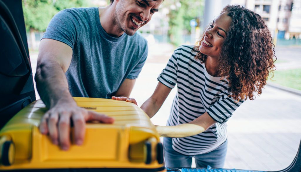 An image of a couple pulling an object out of their vehicle.