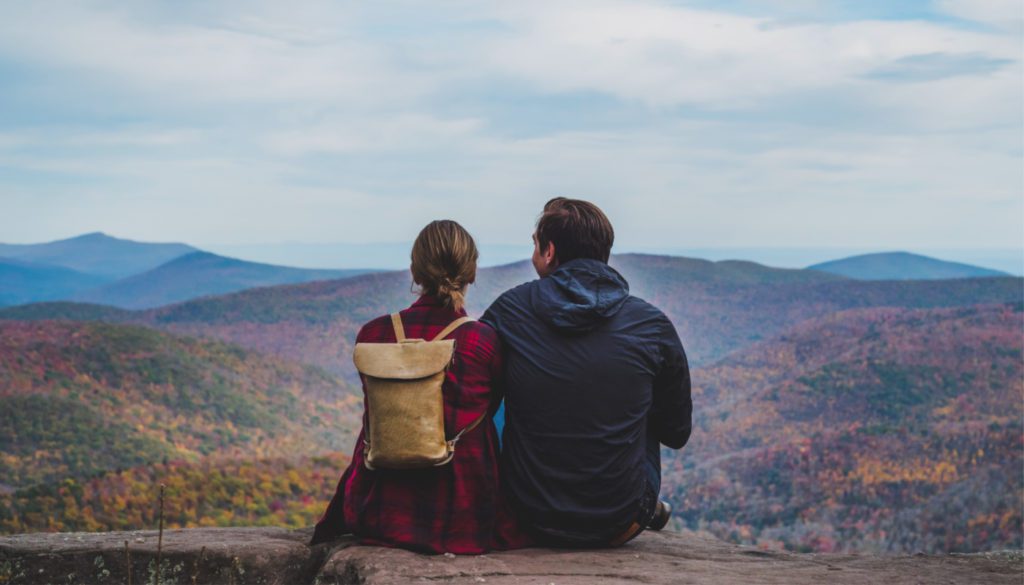 Image: traveling couple sitting together overlooking fall foliage mountain range