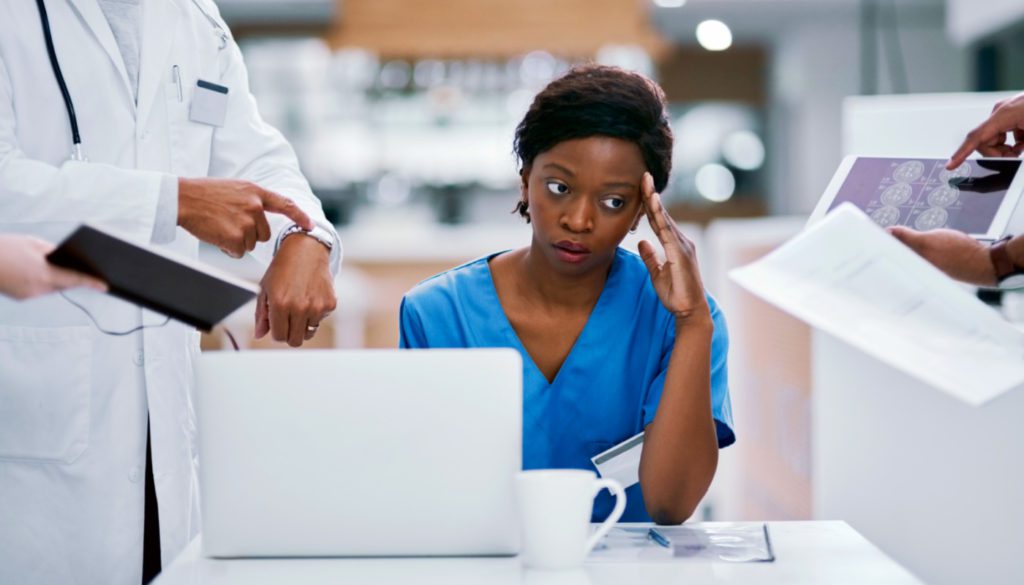 image of a nurse in apparent stress as several medical professionals present her with information and demands