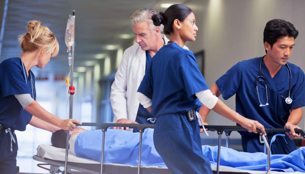 image: medical staff pushing a gurney with a patient laying down in it