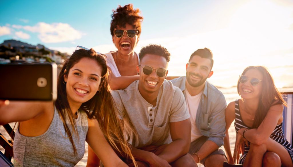 photo of a woman taking a selfie of she and her friends with her phone