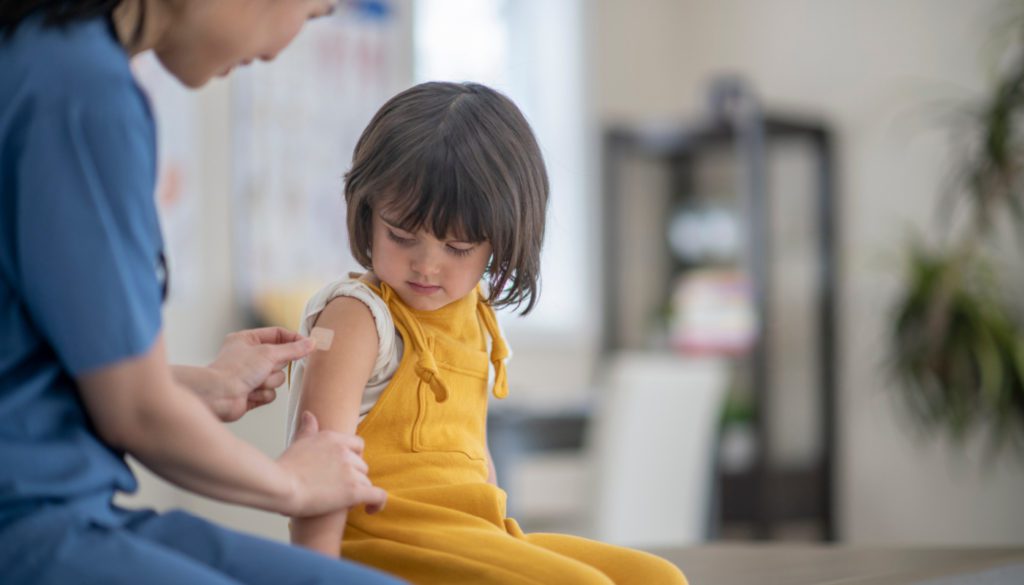 Image: nurse applying a bandaid on a toddler