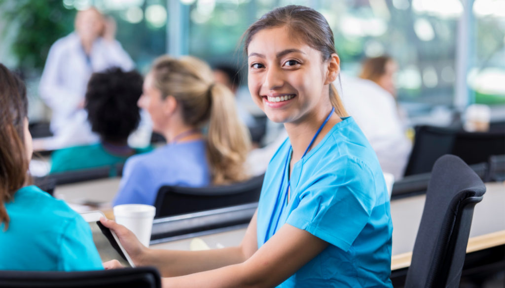 Photo of young woman nurse smiling for the camera while she is in the classroom