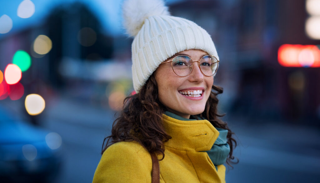 Image: Woman with knit hat, coat, and glasses smiling