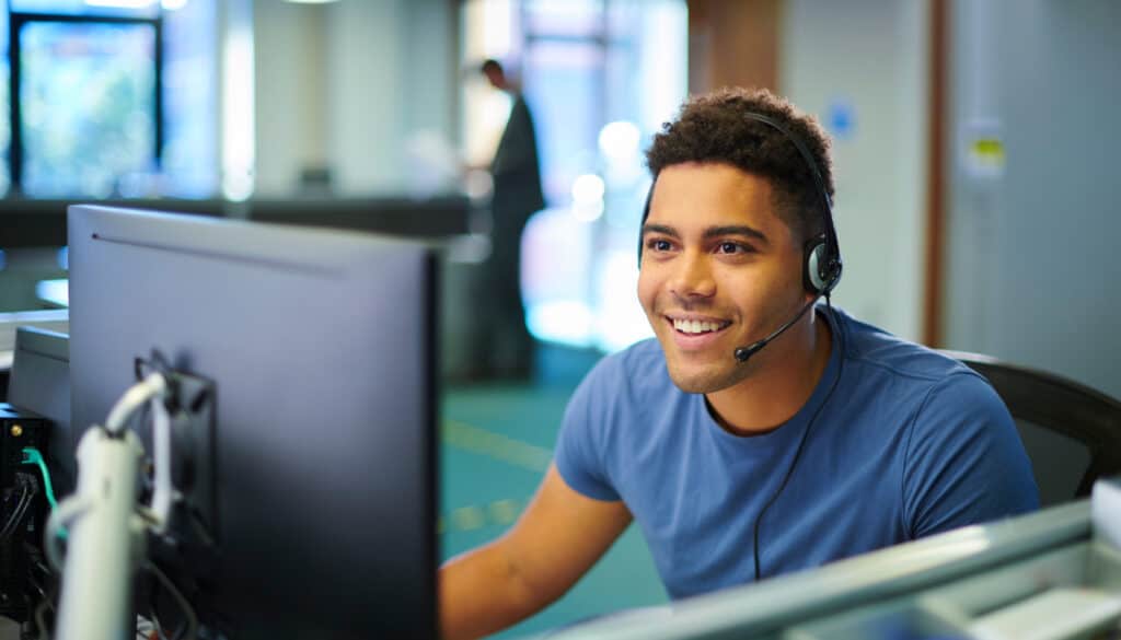 An image of a man working on the computer while wearing a customer service headset