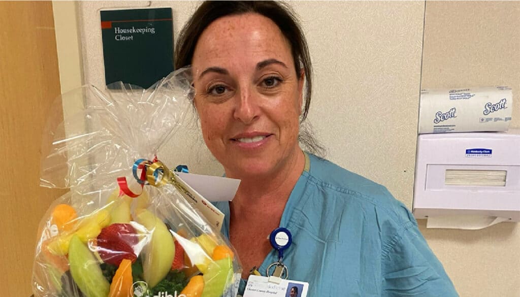 image: travel nurse Kim Patton holding an edible arrangement for winning the Daisy Award nomination for travel nursing