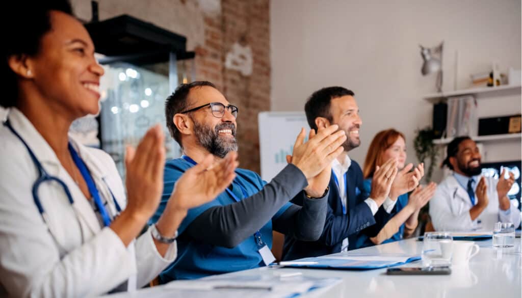 Image of a group of professionals clapping at a table