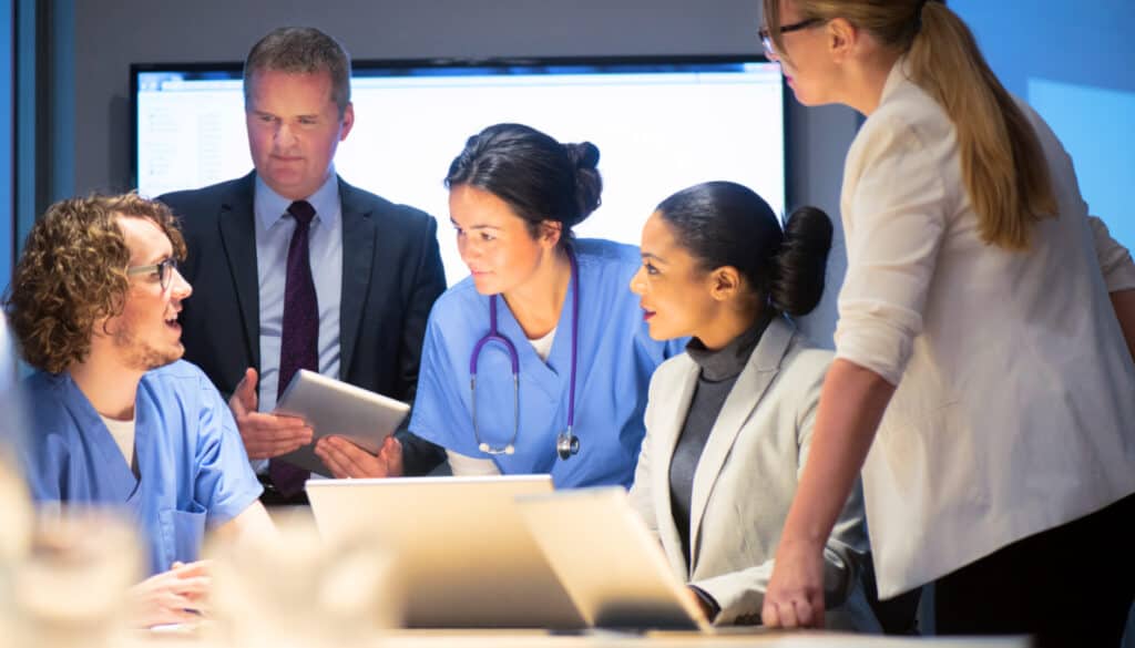 A group of medical professionals looking at a laptop.