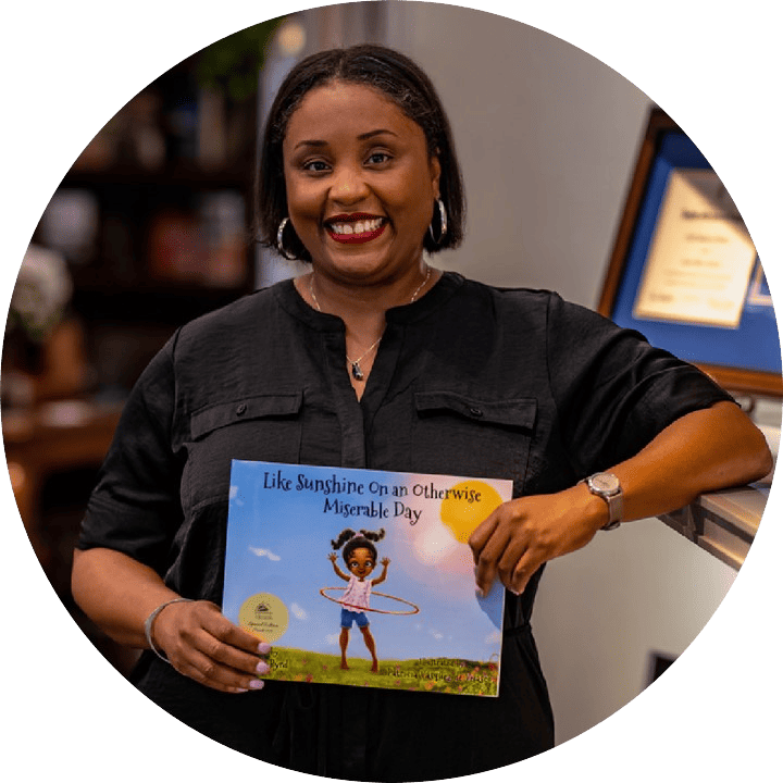 Dr. Kelly Byrd holding up her children's book Like Sunshine On an Otherwise Miserable Day Family Literacy Day Love for Literacy