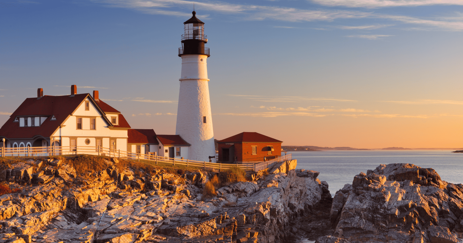 A lighthouse sits on top of a rocky cliff.