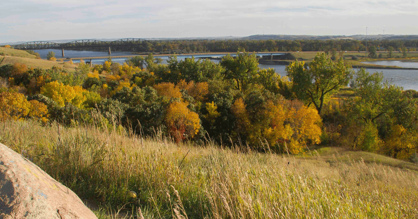 A man sitting on a rock overlooking a river.