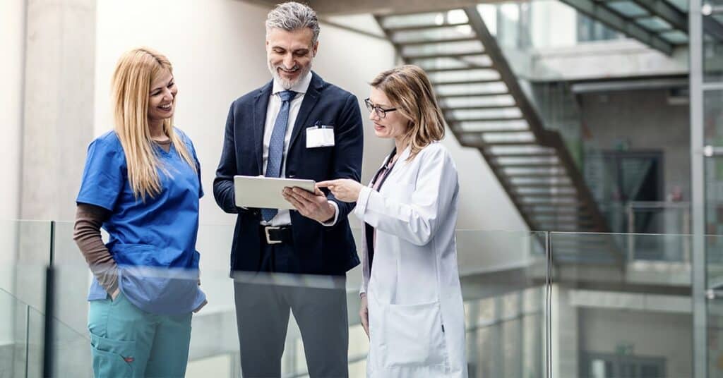 A group of doctors and nurses looking at a tablet.