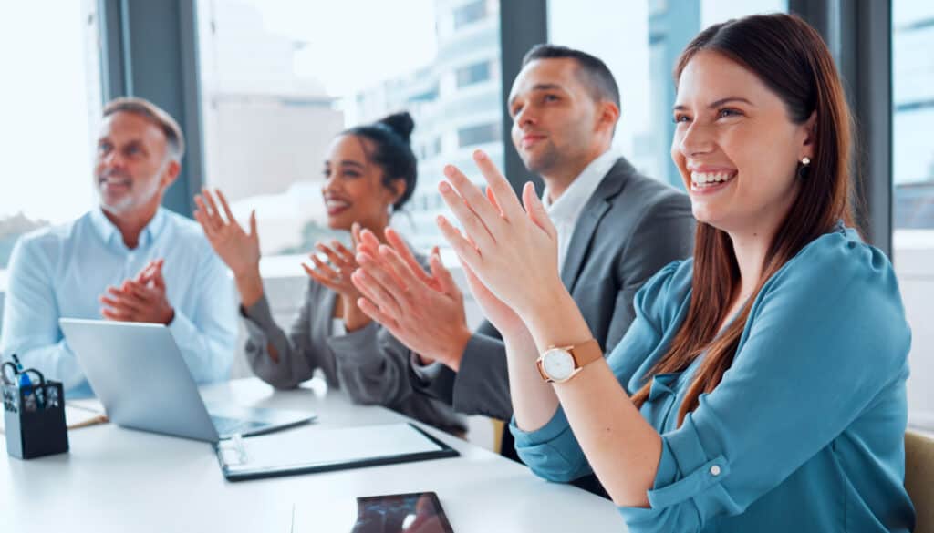 A group of business people clapping at a meeting.