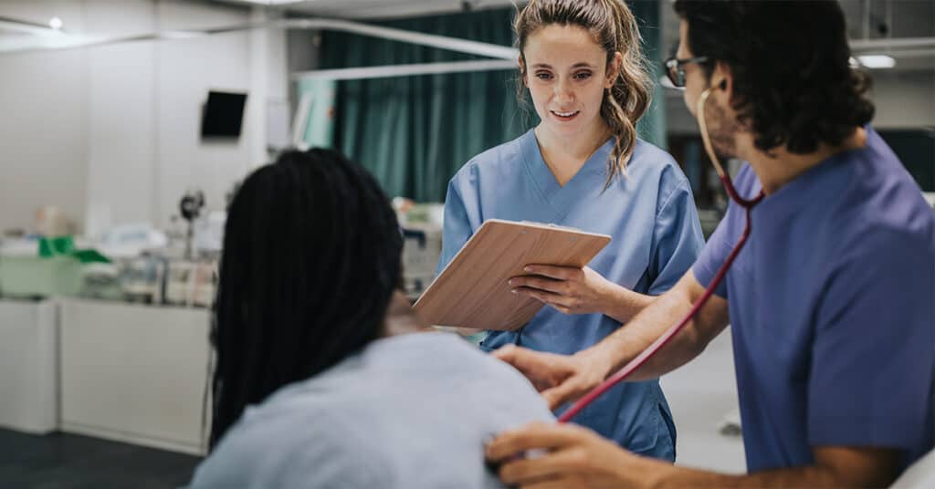 A nurse is holding a stethoscope and talking to a patient.