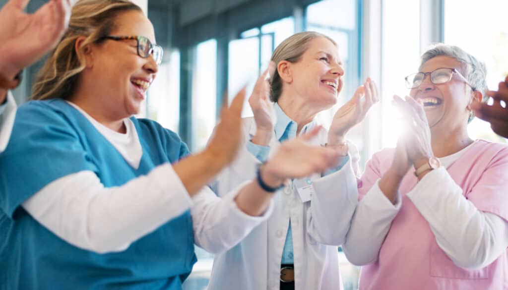 A group of nurses clapping together.
