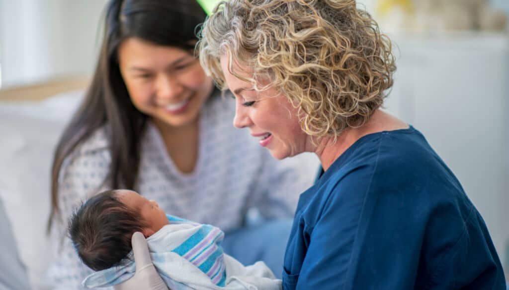 A woman is holding a baby in a hospital bed.