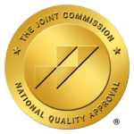 A gold circular seal with "The Joint Commission" and "National Quality Approval" inscribed around it, featuring a central design of three overlapping geometric shapes.