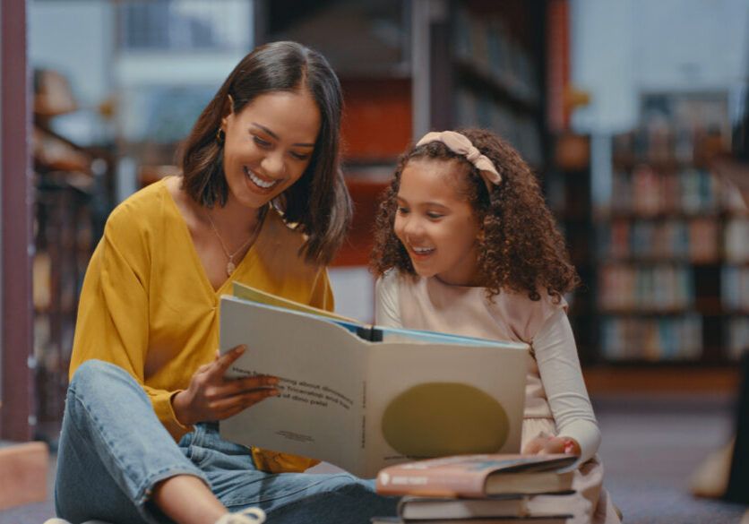 Image: Mother reading book with daughter in a library
