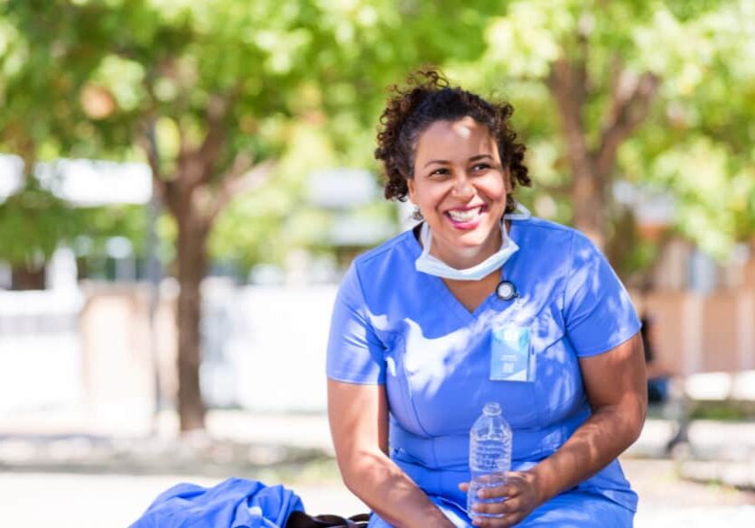 A nurse sitting on a bench with a bottle of water.