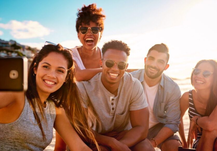 photo of a woman taking a selfie of she and her friends with her phone